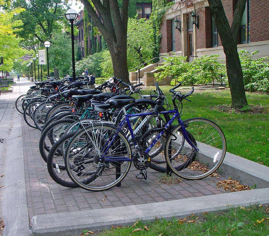 Student bikes parked in front of a university building with traditional bike racks.