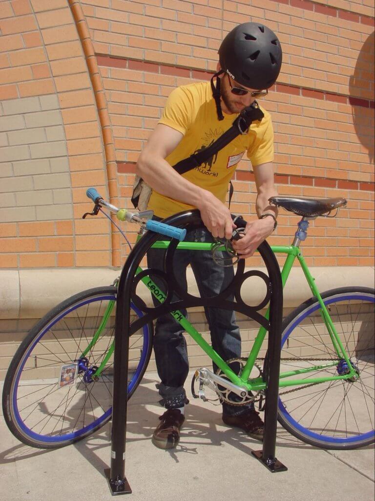 rider locking bike at bike rack
